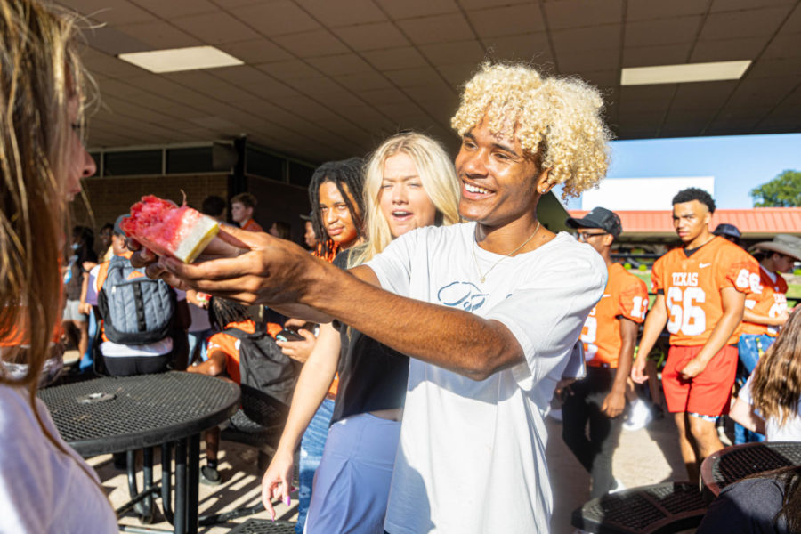 Senior Kavion Rivera holds his watermelon out for his friend to eat. The athletics booster club provided slices of watermelons for the community to enjoy before the pep rally.