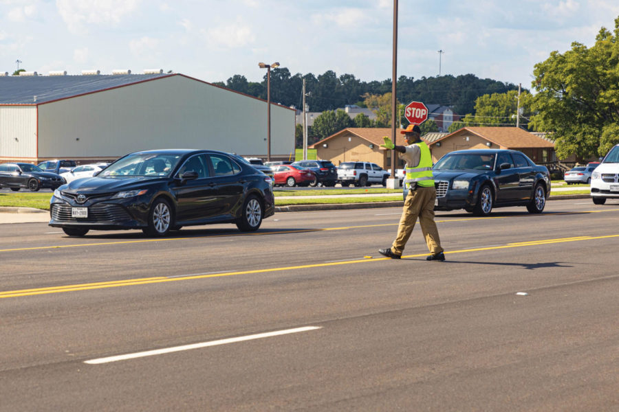 Crossing guard Keith Davis directs traffic in front of the student parking lot after school released. At the beginning of the school year, a new route was approved to reduce the overflow of traffic on Summerhill Rd.