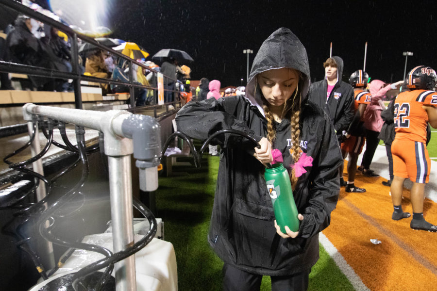 Junior Annabeth Killian fills a water bottle for players during the Texas versus Whitehouse district game. The Tigers were defeated by the Wildcats 32-27, losing the competition for district champs.
