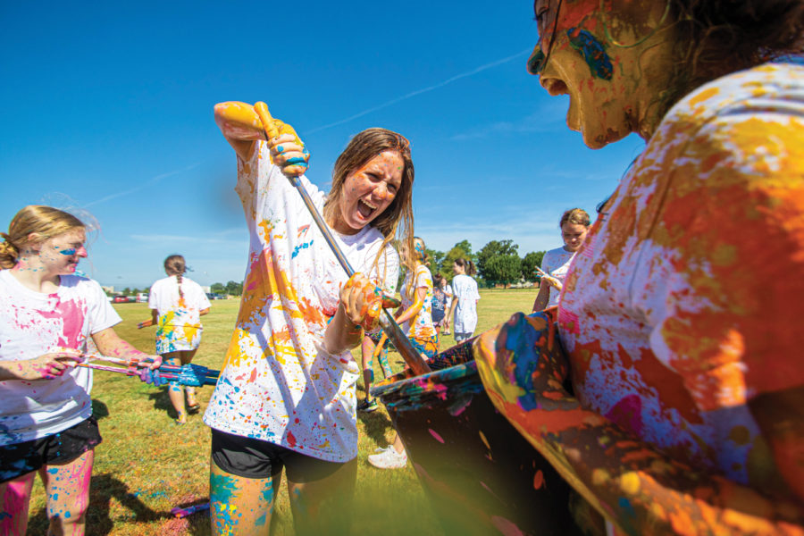 Senior Katherine Sandefur drawls paint from a bucket in the middle of the THS Publications Paint War. On the final day of Publication Boot Camp, Yearbook and Newspaper staff writers throw paint at each other while the photographers take pictures.