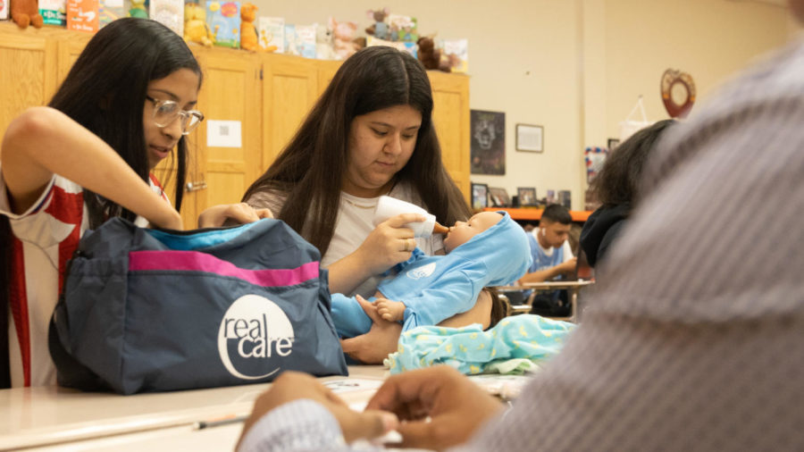 Junior Daisy Ontiveros feeds a robotic baby. In Child Development, students learn skills that will prepare them to raise children, among other things.