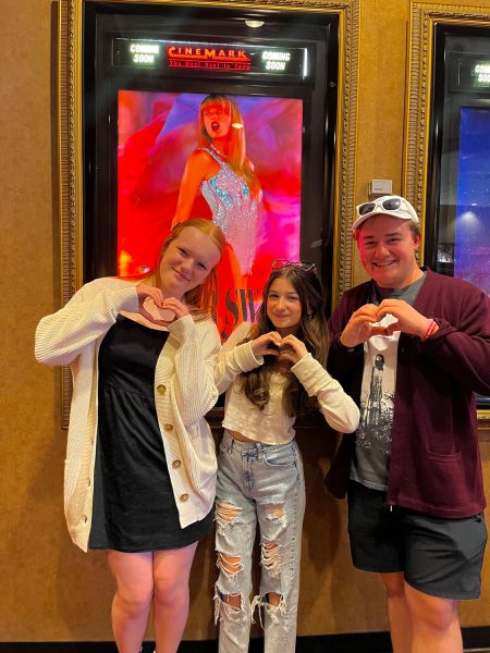 Texas High students Kateleigh Crowson, Riley White and Tyler Unger stand with their hands in the shape of a heart before watching Taylor Swifts Eras Tour. Swift recently released a movie of her tour worldwide.