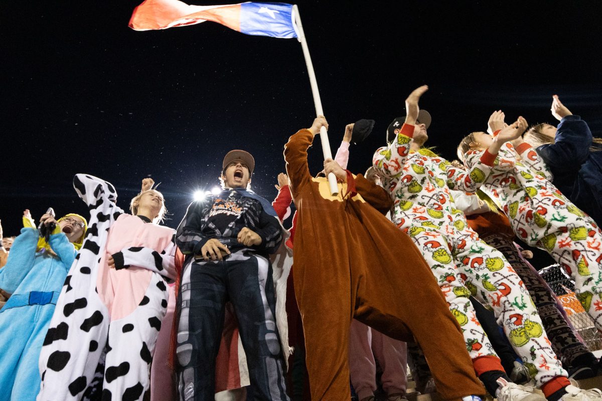 Wearing his onesie, senior David Barlow waves the Texas flag in the student section. The Texas Tigers defeated the visiting Tigers of Terrell in round one.