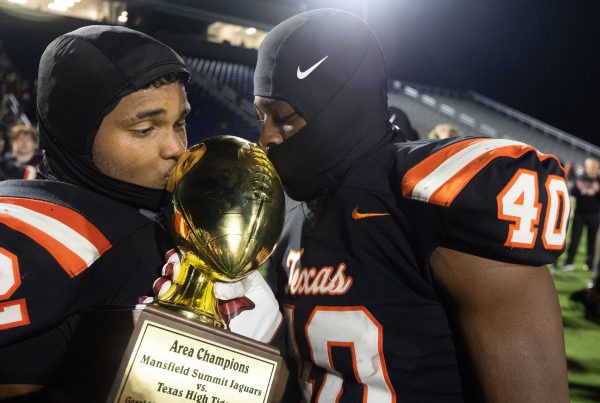 Junior Isaiah Dowden and sophomore Eshayland Cooper kiss the Area Championship trophy at the end of the round two playoff game against Mansfield Summit on Nov. 17, 2023. Dowden was named player of the game. 