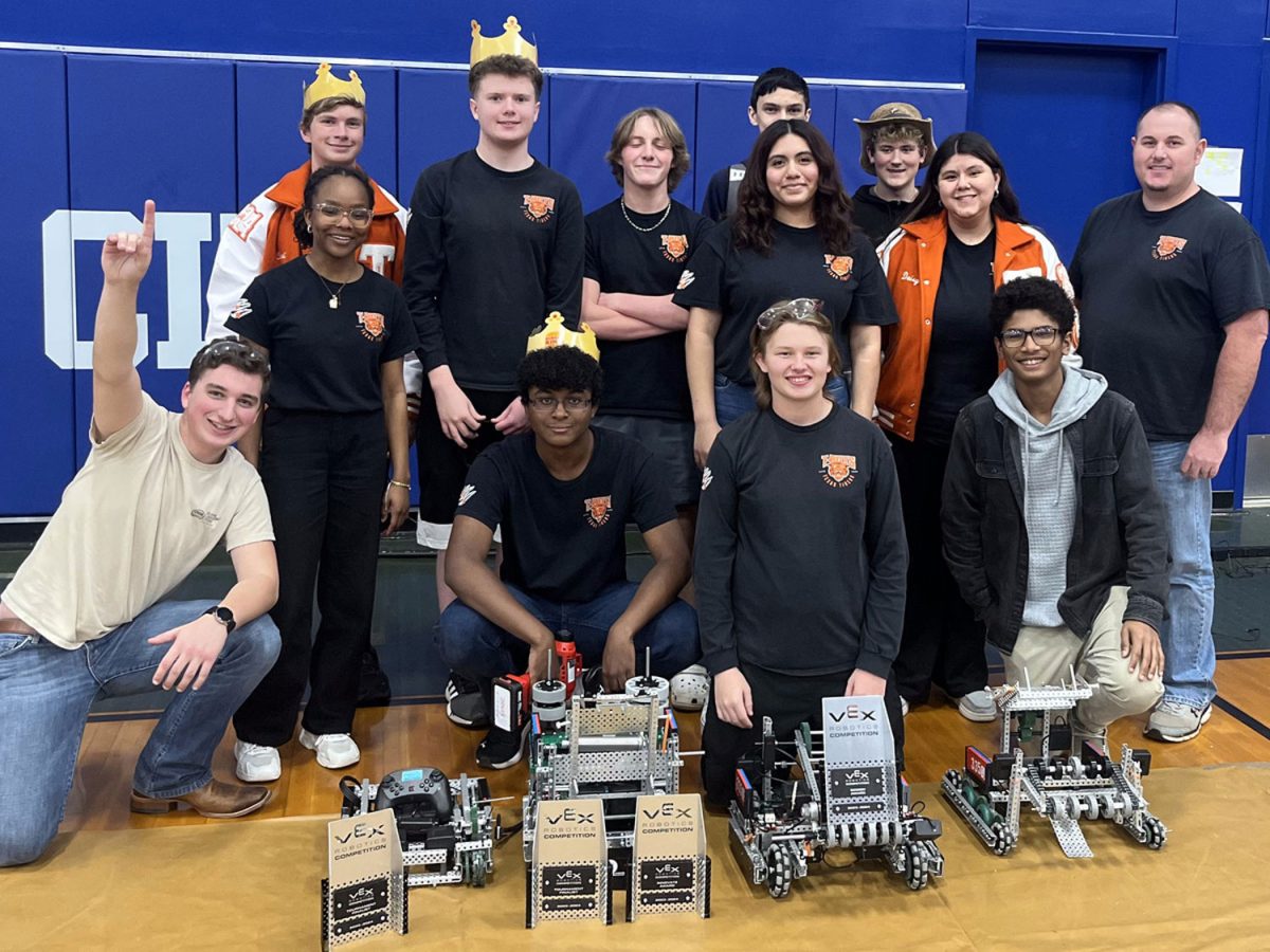 Standing in excitement, the robotics team  smiles after their best competition of the year. The team qualified for UIL state.