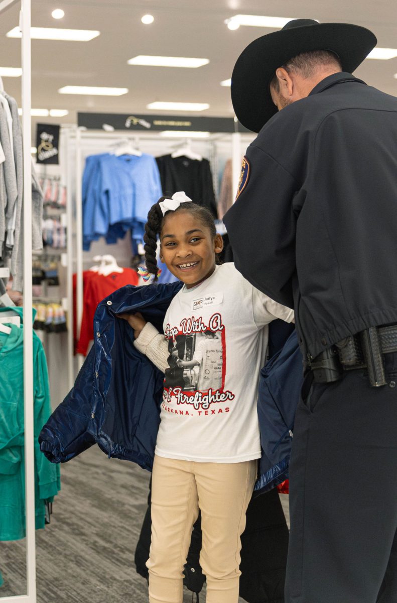 Laughing with her officer, Janya Powell tries on a new coat when choosing her gifts for Christmas.