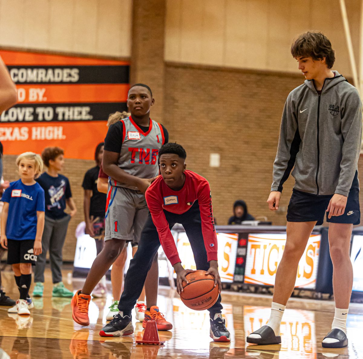 Junior Alex Orr watches as a camper dribbles a ball in the basketball and cheer camp. The camp was held for the first time since 2020 due to COVID-19. 