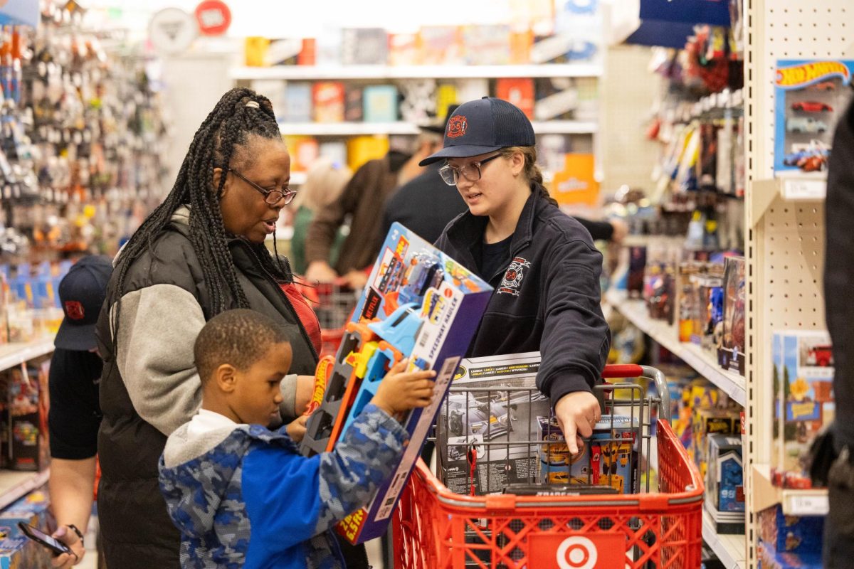 Volunteer firefighter and Texas High School junior Bella Cornelius points to gifts in the shopping cart while participating in Shop with a Cop. This year, shoppers spent $150 on their holiday gifts.