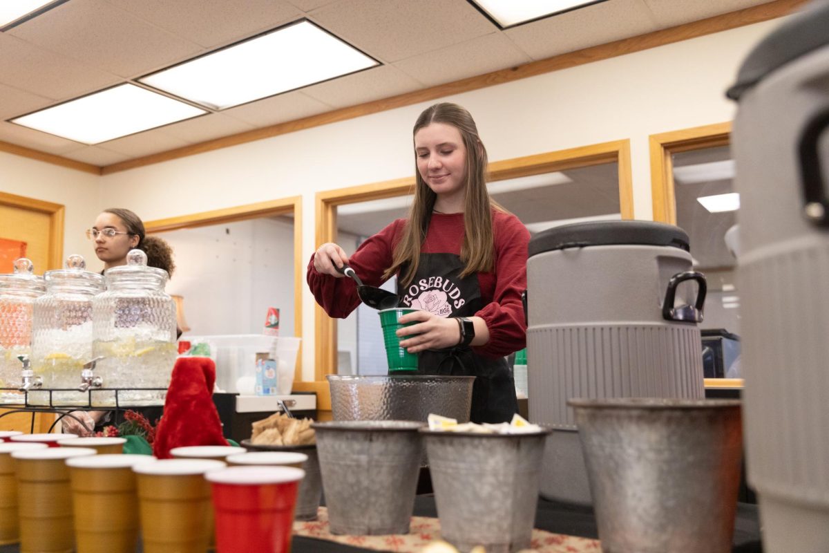 Sophomore+Meredith+McPhaul+pours+drinks+into+cups+to+serve+to+teachers.+The+Teachers+Tea+took+place+in+the+library+on+Dec.+6%2C+2023