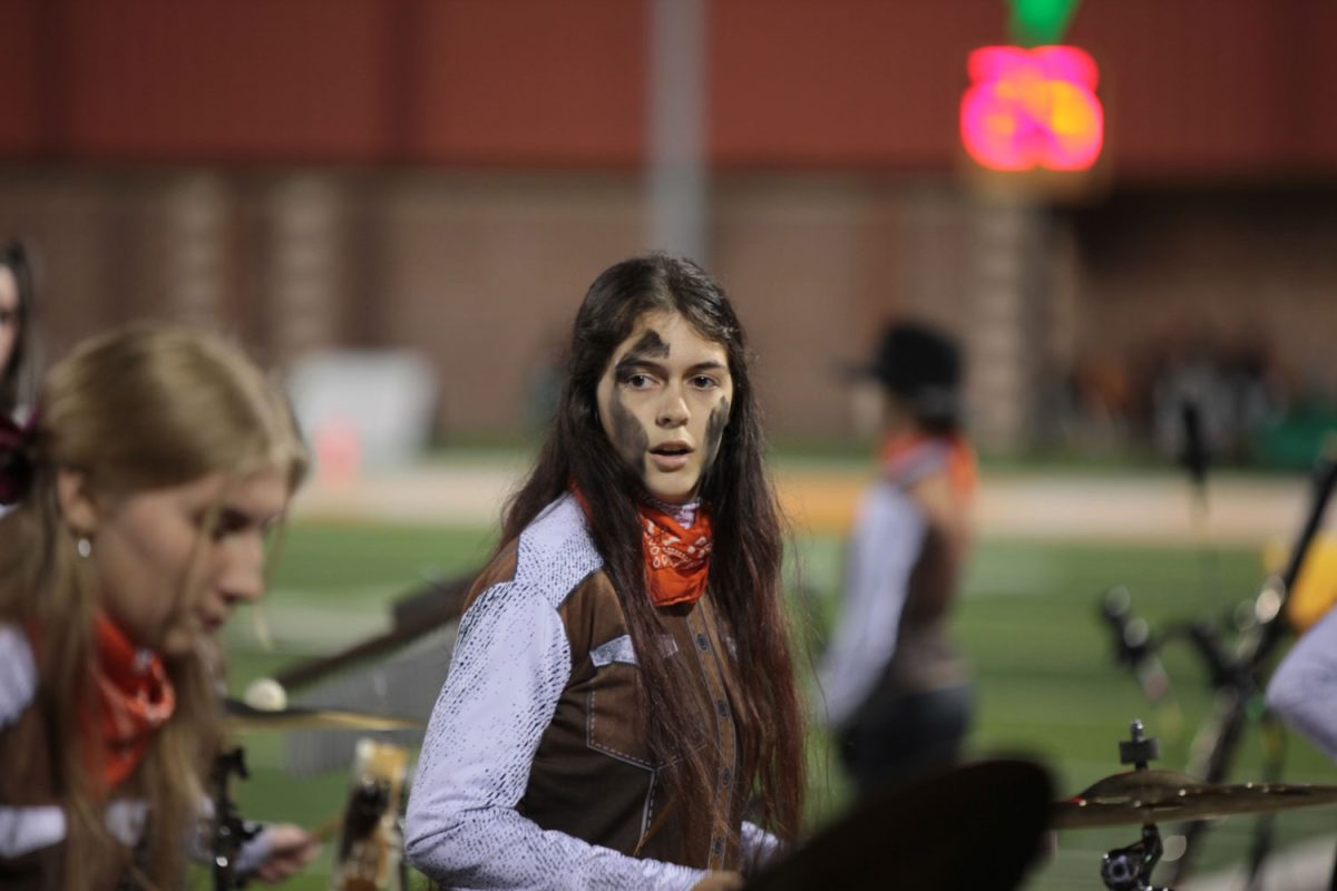 Looking to her bandmate, senior Lourdes Quijas performs during half time at a football game. Quijas has been in band since her freshman year. 