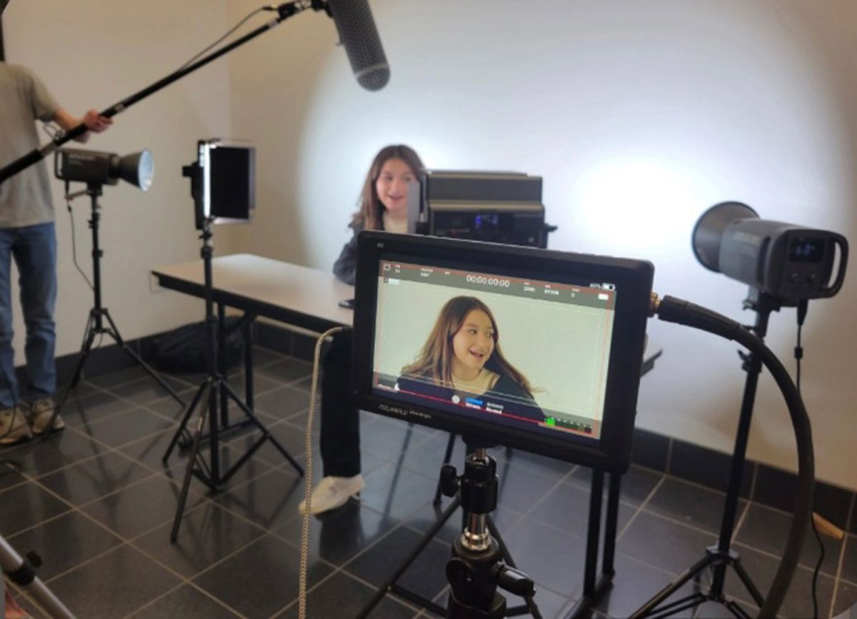 Light shining on her, senior Riley White sits in front of a camera while students practice their UIL Film skills. 