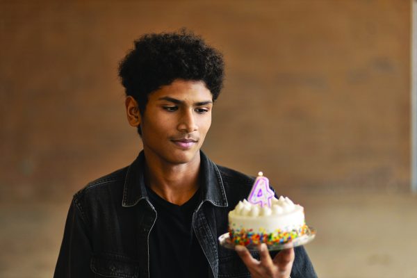 Sophomore Kunan Anjum holds a small birthday cake with a number four candle. As a tradition, every leap year his family puts on a leap year age candle instead of his actual age.