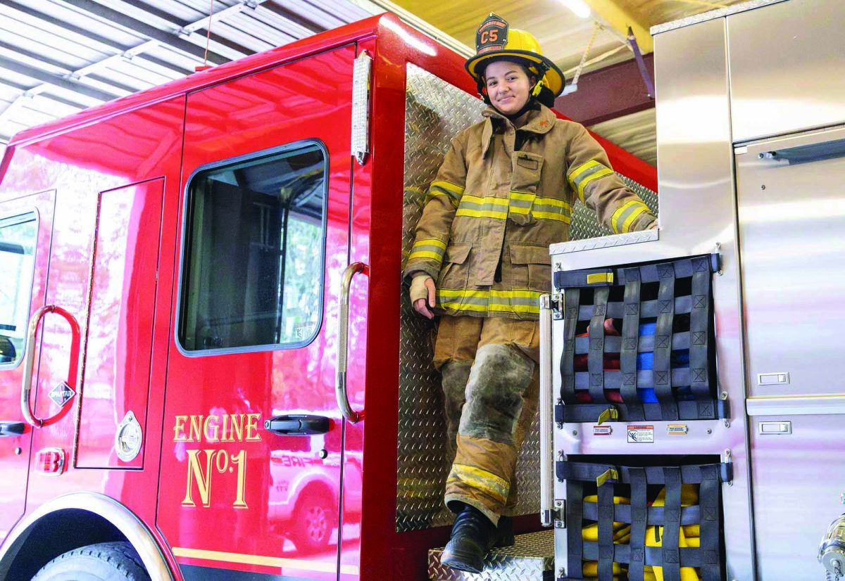 Junior Isabella Cornelius poses in front of a fire truck wearing her protective uniform.  She volunteers at the Red Lick Fire Department in addition to being a full-time high school student.