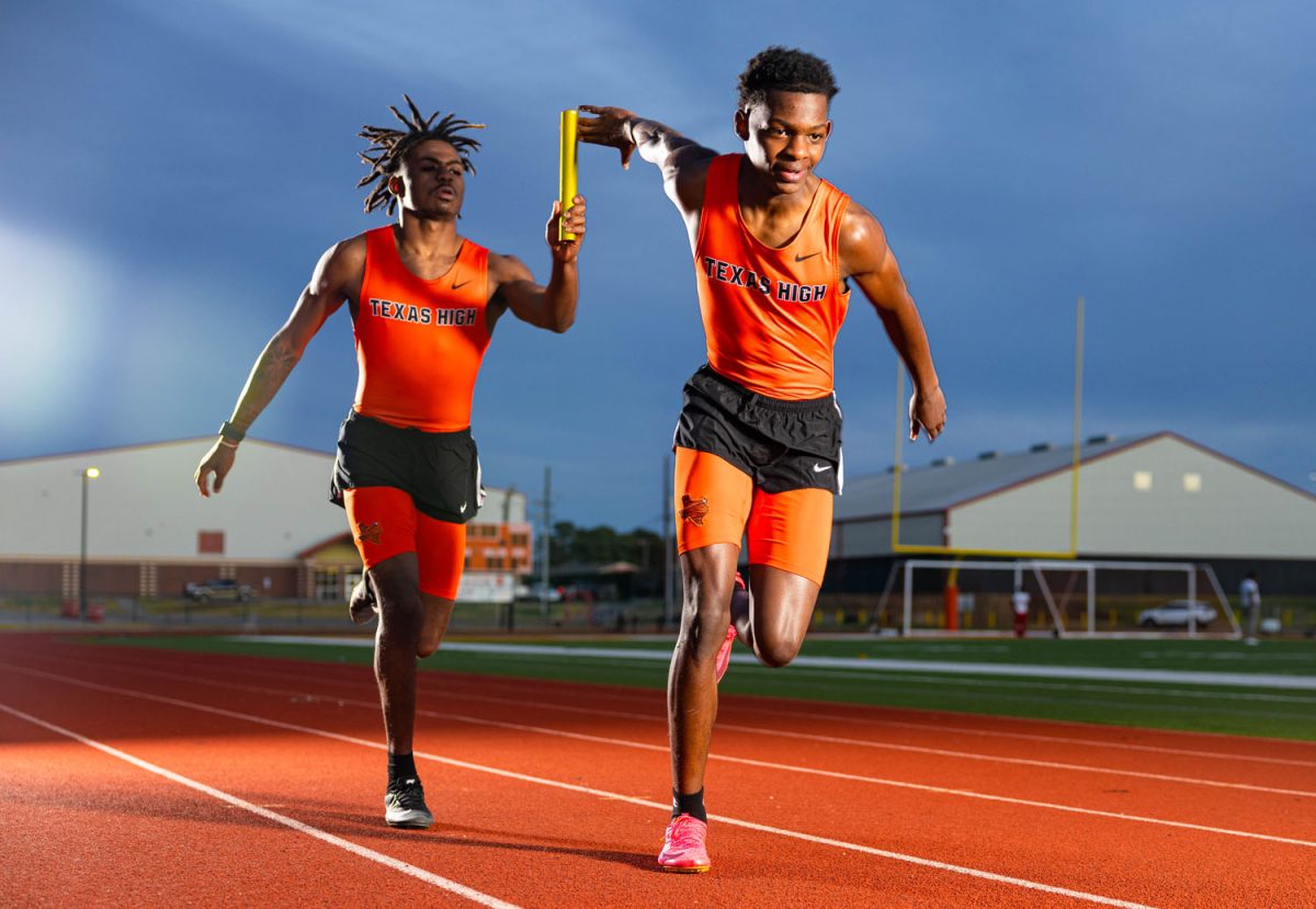 Sophomore Justin Arnold receives the baton from junior Kendrevion Boyce in a relay handoff. Arnold will be competing multiple events for the Tigers this season.