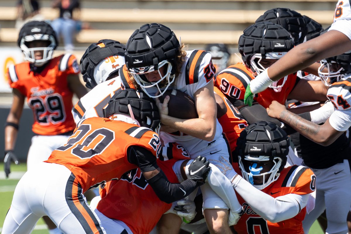 Senior Peyton Walker tackles a player on the opposing team during the Orange vs White Watermelon Supper scrimmage. Under the new leadership of senior quarterback Kameron Wrightner, the team works to build chemistry and adapt to his style of play, which challenges defenses and demands a versatile approach.