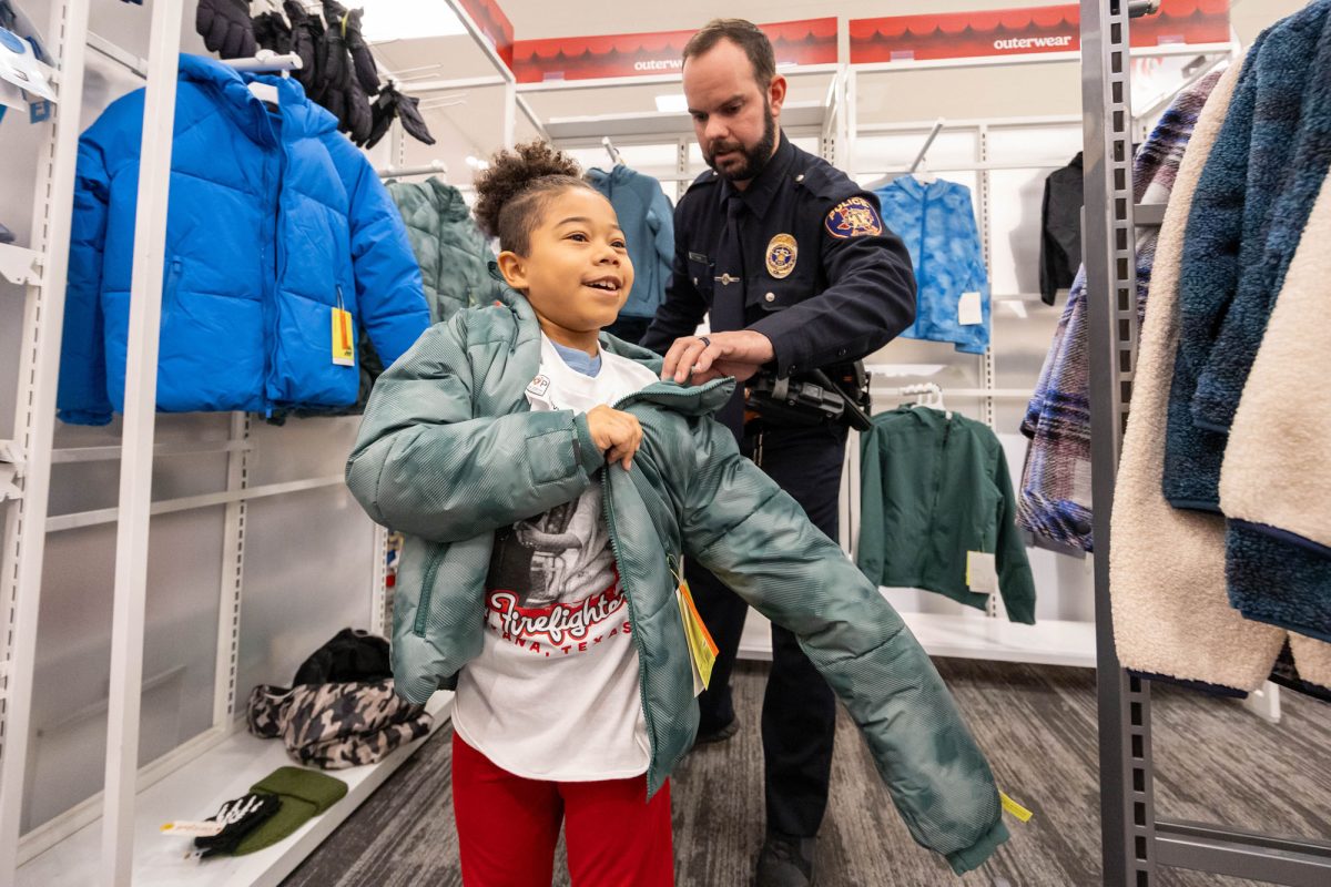 As they try on a new jacket, TISD Student and TTPD Officer at the annual Shop with the Cop & Firefighter Dec. 2, 2025.