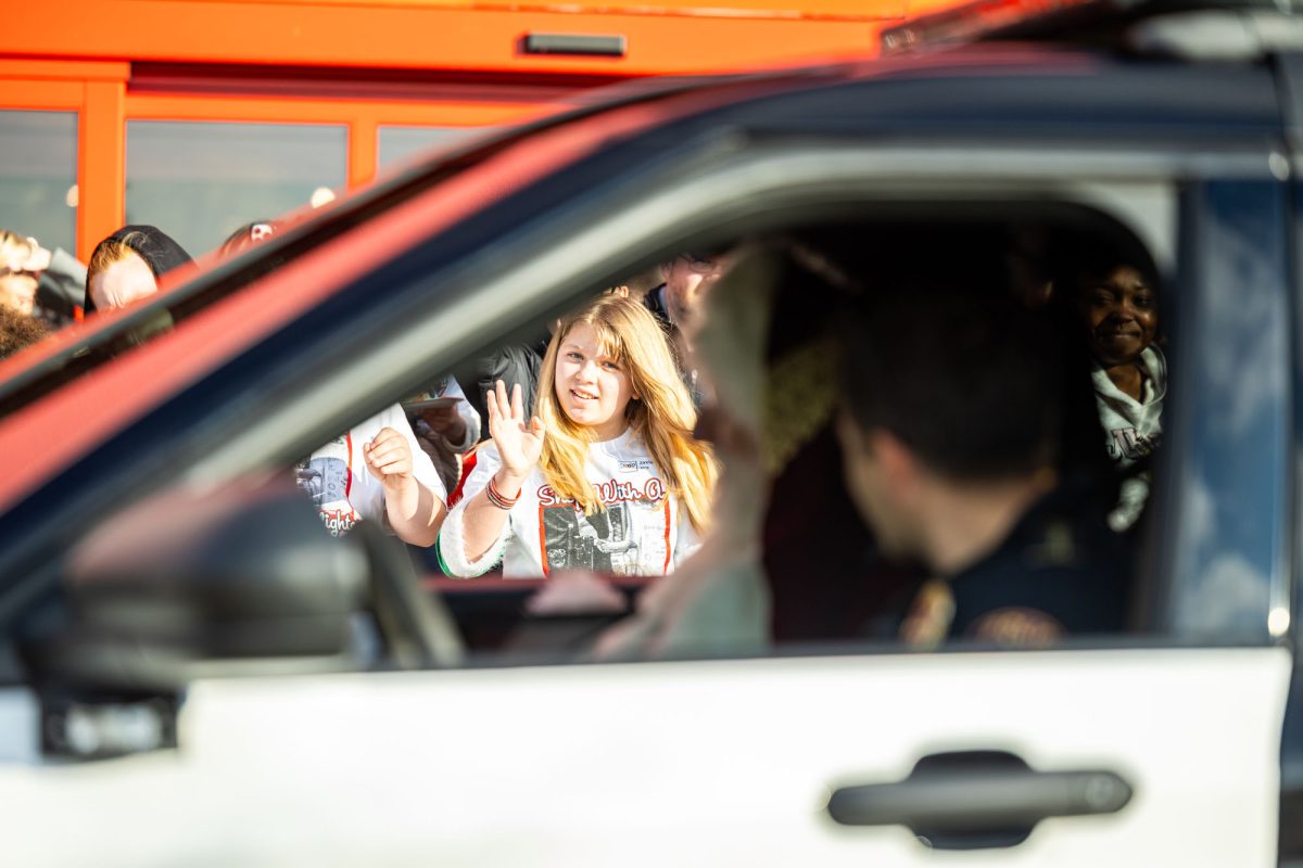 A TISD Student waves as a TTPD Officer and Santa Clause drive by at the annual Shop with a Cop & Firefighter Dec. 2, 2025.